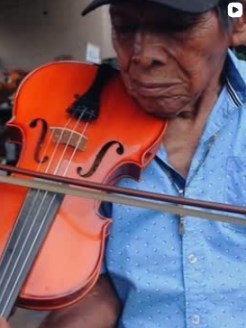 Foto real de un músico tocando tamborito en una noche de folclore en La Divina Commedia El Valle